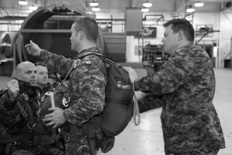In his role as jumpmaster, Capt Scott Moody, Officer Commanding 60th Company, adjusts the equipment of Sgt Matt Kohler prior to a training session.